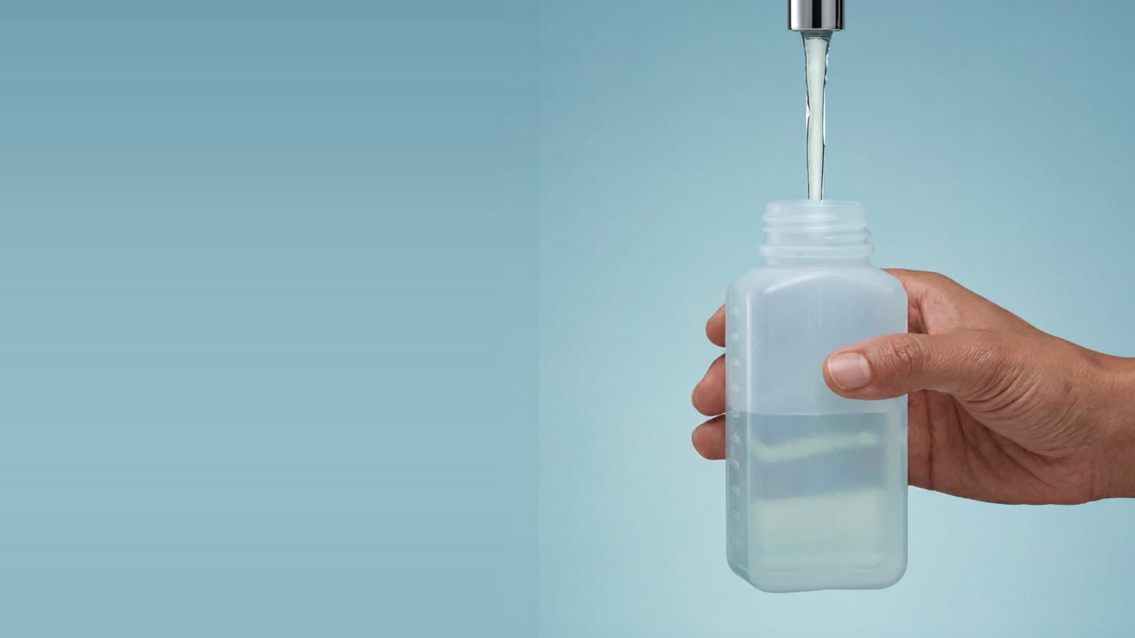 Tap water running into a lab sample bottle held in one hand