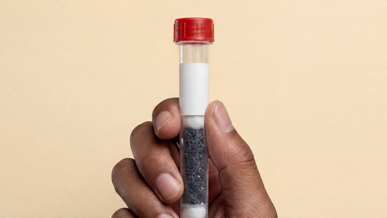 A hand holding an air sampling tube against a warm backdrop