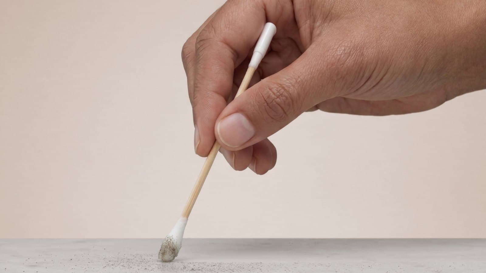 A hand pressing a cotton swab against a stone countertop