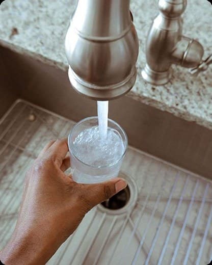 A sample bottle being filled at a kitchen tap
