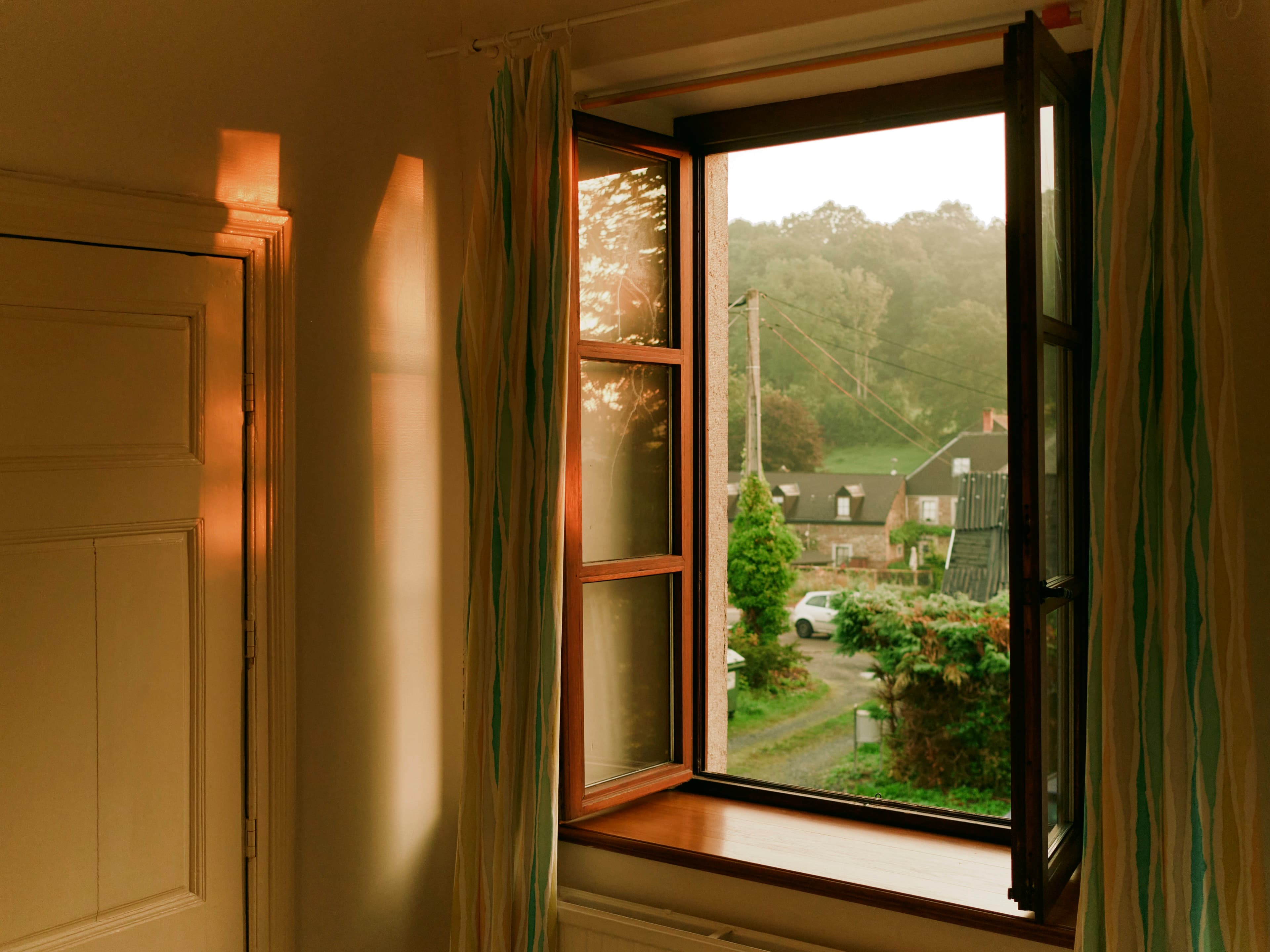 An open window looking out onto trees and gardens